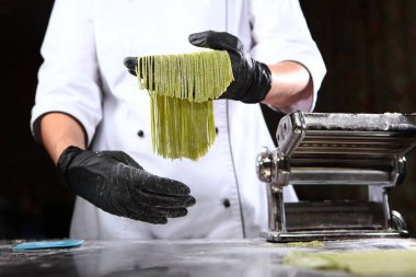 Ispanaklı ev yapımı hamur. Şef elinde ıspanak ilaveli hamurdan yeni pişmiş bir spagetti tutuyor. Faydalı bir malzeme. Tanımlanamayan kişi. Evde makarna yapmak için makine.