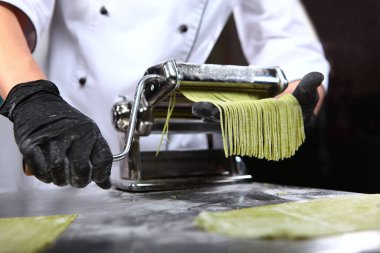 Ispanaklı spagetti için hamur hazırlıyorum. Sağlıklı yemek. Organik yiyecekler. Tanımlanamayan kişi. Karanlık arka plan. Makarna pişirme makinesi. Alt görünüm.