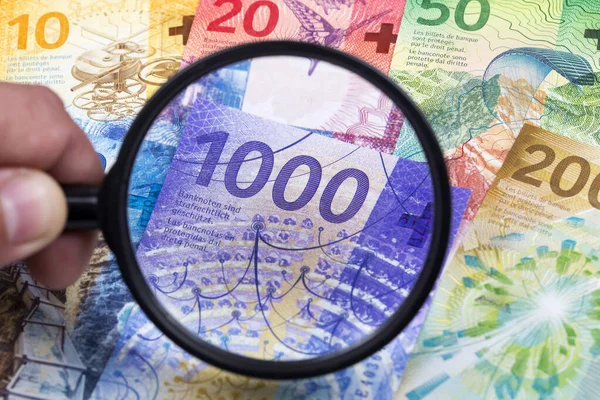 Swiss money in a magnifying glass a business background