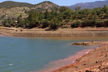 Sıcak güneşli gündüz saatlerinde mavi nehrin manzarası ve arka planda dağlar