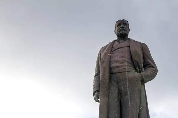 Old stone statue of man on grey sky background