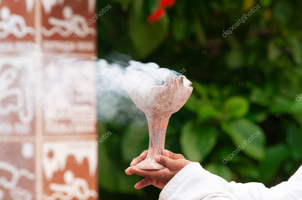 Young Mayan man holds in his hands a brazier lit with Copal smoke - Ancient Mayan tradition of purification and meditation, Mexico, America