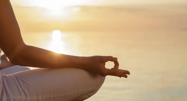 Meditasyon kavramı. Bir kadında lotus pozisyonu, parmak mudra günbatımı ve sakin deniz karşı gövde bölümü.