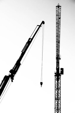 İnşaat alanındaki vinçlerin siyah beyaz görüntüsü.
