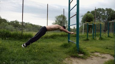 Spor malzemelerinde trisepsler üzerinde egzersiz yapan genç kaslı bir atlet. Spor alanında spor yapan erkek üstsüz bir sporcu. Doğada güçlü bir sporcu eğitimi. Sağlıklı yaşam tarzı kavramı.