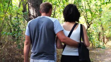 Mutlu çift yaz ormanında yolda yürüyor. Vahşi ormanlık alanda romantik bir çift geziyor. Sevgililer doğada birlikte vakit geçirirler. Aşk ve mutluluk kavramı. Yavaş çekim