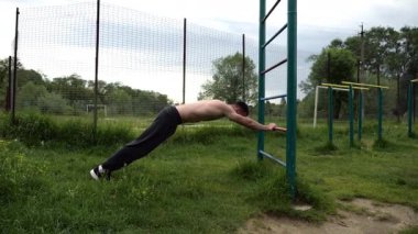 Spor malzemelerinde trisepsler üzerinde egzersiz yapan genç kaslı bir atlet. Spor alanında spor yapan erkek üstsüz bir sporcu. Doğada güçlü bir sporcu eğitimi. Sağlıklı yaşam tarzı kavramı.