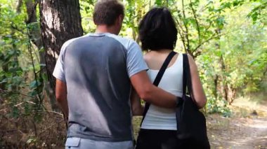 Mutlu çift yaz ormanında yolda yürüyor. Vahşi ormanlık alanda romantik bir çift geziyor. Sevgililer doğada birlikte vakit geçirirler. Aşk ve mutluluk kavramı. Yavaş çekim