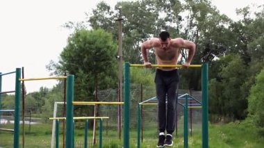 Cesur üstsüz sporcu doğada yatay çıtada şınav çekiyor. Güçlü ve kaslı adam spor alanında antrenman yapıyor. Genç atletik adam dışarıda egzersiz yapıyor. Aktif ve sağlıklı yaşam tarzı kavramı.