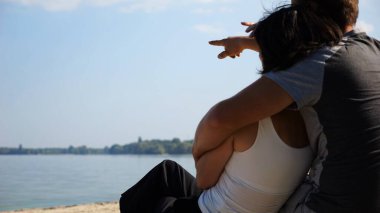 Kumsalda tahta kütüğün üzerinde otururken mutlu çift kucaklaşması. Güneşli bir günde deniz manzarasına hayran olan romantik bir çift. Sevgililer tatil köyünde birlikte vakit geçirirler. Yaz tatili ya da tatil kavramı. Yavaş çekim