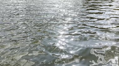 Yazın güneşle aydınlatılan göletin manzara yüzeyi. Güneşli bir günde deniz manzarası ve küçük dalgalar. Güzel yaz doğa manzarası. Huzur sahnesi kavramı. Yavaş çekim