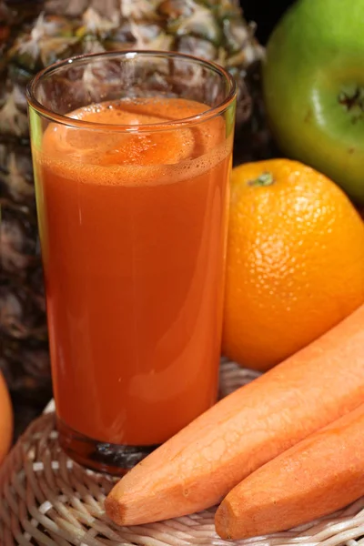 macro delicious fresh carrot juice in a glass on a background of vegetables and fruits