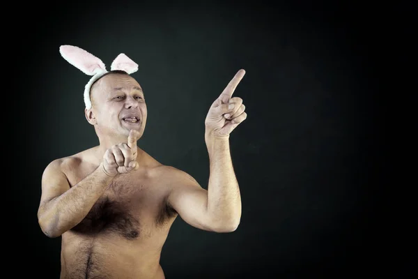 funny portrait of a man with a pink rabbit ears on gray background studio