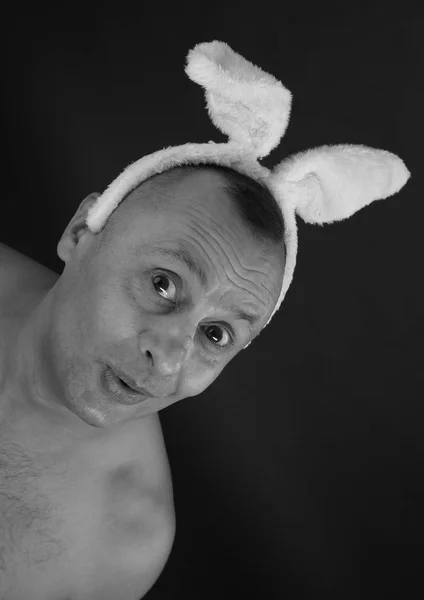 funny portrait of a man with a pink rabbit ears on gray background studio