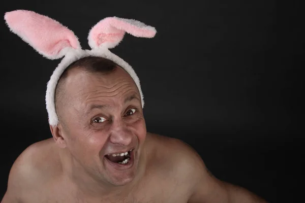 funny portrait of a man with a pink rabbit ears on gray background studio