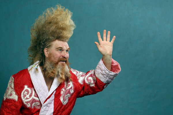 Портрет харизматичного взрослого мужчины с бородой и высоким ирокезом в студии на тёмном фоне
 