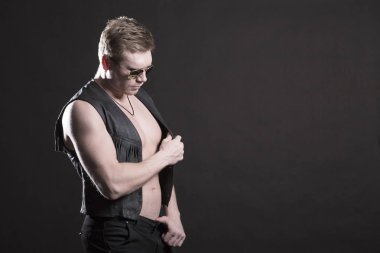 Yakışıklı erkek vücut geliştirmeci deri yelek siyah bir zemin üzerine