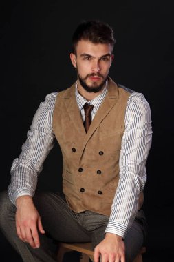 portre portre sakal giyen ile güzel karizmatik genç adamın pantolon, gömlek, yelek ve bir koyu arka plan stüdyo kravat
