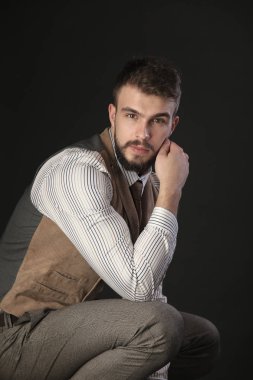 portre portre sakal giyen ile güzel karizmatik genç adamın pantolon, gömlek, yelek ve bir koyu arka plan stüdyo kravat