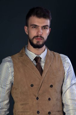 portre portre sakal giyen ile güzel karizmatik genç adamın pantolon, gömlek, yelek ve bir koyu arka plan stüdyo kravat