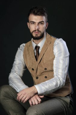 portre portre sakal giyen ile güzel karizmatik genç adamın pantolon, gömlek, yelek ve bir koyu arka plan stüdyo kravat