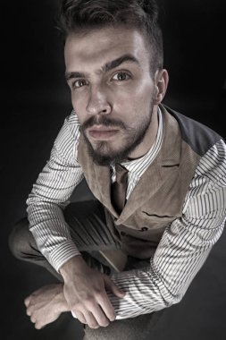 portre portre sakal giyen ile güzel karizmatik genç adamın pantolon, gömlek, yelek ve bir koyu arka plan stüdyo kravat