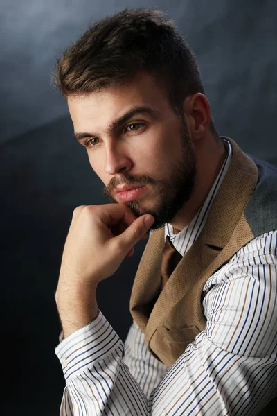 portre portre sakal giyen ile güzel karizmatik genç adamın pantolon, gömlek, yelek ve bir koyu arka plan stüdyo kravat