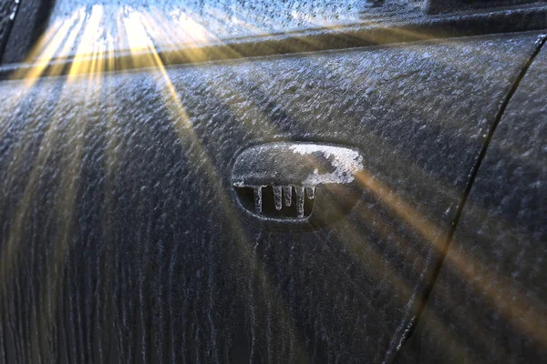 closeup fragment of the ice-covered car in the sun frosty morning