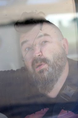 Yüzünü cama bir sakal ve bıyık gözlük takan üzücü bir yetişkin erkek portresi closeup preslenmiş