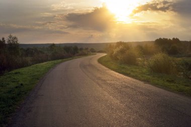 Şafak vakti, sel basmış çayırların ortasında ıssız bir yol boyunca seyahat etmek.