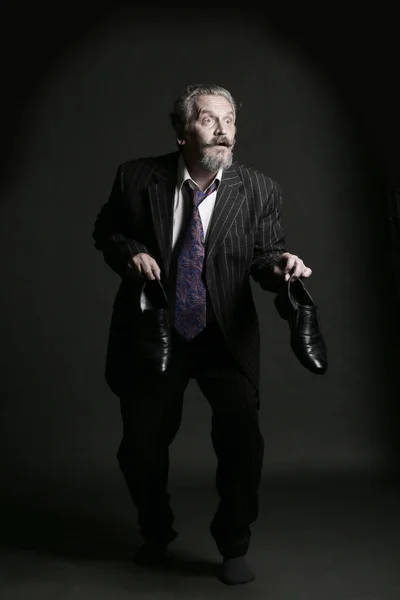 closeup portrait of an adult male with a mustache and beard sneaks with shoes in hand