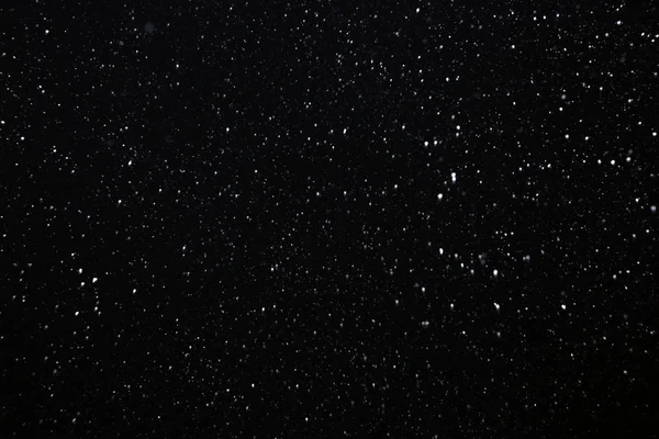 closeup background texture of snowflakes during a snowfall on a black background