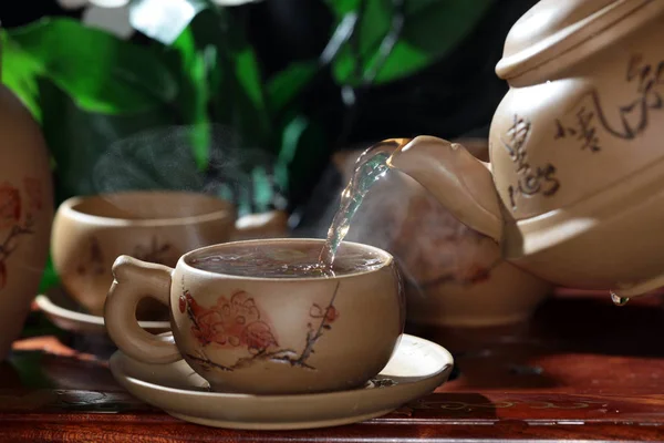 Чай Наливают Чайника Глиняную Чашку Размытом Цветочном Фоне — стоковое фото