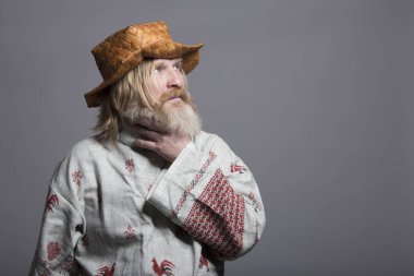 Slavic bearded man in a beautiful painted shirt and a birchbark hat clipart