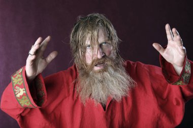 Kırmızı gömlek stüdyosunda uzun sakallı, bıyıklı ve ıslak sarı saçlı kutsanmış birinin yakın plan portresi.