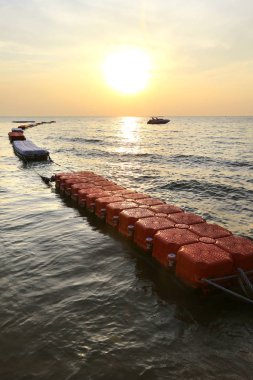 Gün batımında denizde yüzen bariyerler