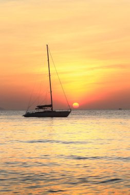 Deniz manzaralı gün batımı ve Tayland kıyılarında sönük yelkenli bir tekne.