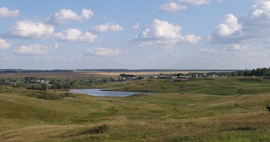 Yaz manzarası bulutlu çayırların ve nehir kıyısındaki köyün üzerinde