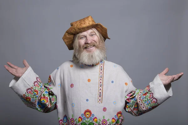 Slavic bearded man in a beautiful painted shirt and a birchbark hat