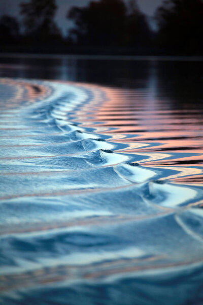 close-up amazing wavy trace of the boat on the river at sunset