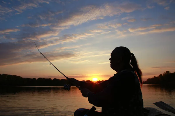 秋日日落时 一个人在河上的船上 手里拿着一根钓竿 他的肖像 — 图库照片