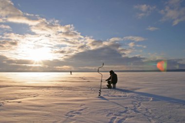 winter landscape fisherman fishing on the estuary Eek river at sunset clipart