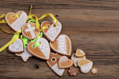  Sarı kurdeleli kalp şeklinde makro zencefilli kurabiye, ahşap arka planda çiçekler.