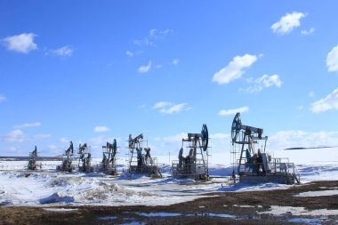 Endüstriyel peyzaj petrol pompaları mavi gökyüzünün arka planında ve güneşli bir bahar sabahında beyaz bulutlarda