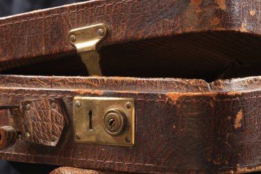 Eski model deri valizin üzerindeki kilit ve bağlayıcıların yakın plan parçaları kahverengi.