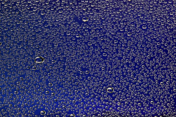 青い背景のガラスの上の密接なテクスチャ水滴 — ストック写真