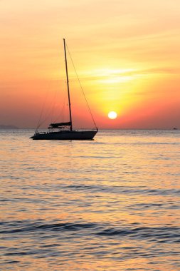 Deniz manzaralı gün batımı ve Tayland kıyılarında sönük yelkenli bir tekne.