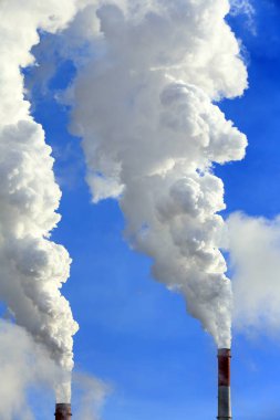 Mavi gökyüzüne karşı bitkinin bacasından izole edilmiş beyaz duman.