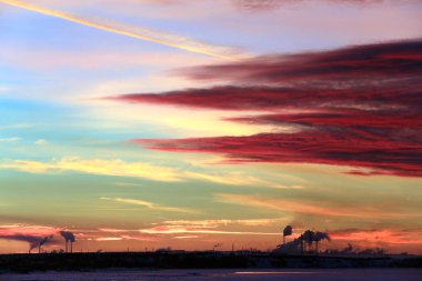 Kış manzarası nehirdeki buza kırmızı gün batımı ve ufuktaki boru bitkisi