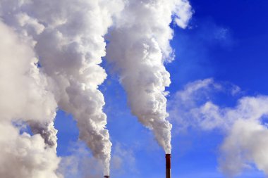 Mavi gökyüzüne karşı bitkinin bacasından izole edilmiş beyaz duman.